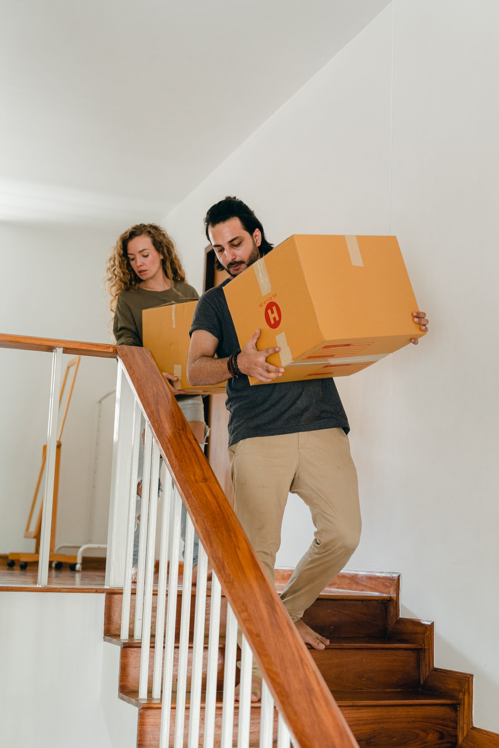 Couple carrying boxes downstairs while moving out of a Dubai home